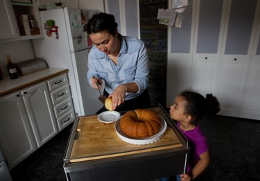 Liz Vargas with  her daughter Layla presents a slice of her rum cake in Montreal Tuesday, November 4, 2014. The Montreal woman has started a business dedicated to making her Azucar & Ron rum cakes.