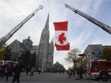 A Canadian flag is held aloft in front of a cathedral in Longueuil, Que., Saturday, Nov. 1, 2014 before a funeral for warrant officer Patrice Vincent, who died after being hit by a car driven by an attacker with known jihadist sympathies. The 53-year-old Vincent was killed on Oct. 20 in the parking lot of a shopping mall in Saint-Jean-sur-Richelieu, southeast of Montreal.