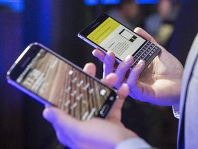 A journalist compares the new BlackBerry Passport device (right) to an existing Android device at the Passport's launch in Toronto Sept. 24, 2014.