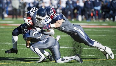 Toronto Argonauts' Steve Slaton (20) is tackled by Montreal Alouettes' Brian Brikowski, right, and Mitchell White during first half CFL football action in Montreal, Sunday, November 02, 2014. THE CANADIAN PRESS/