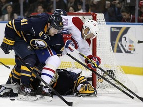 Buffalo Sabres defenceman Andrej Meszaros (41), of Slovakia, checks Montreal Canadiens centre Manny Malhotra (20) off the puck in the goal crease as Sabres goaltender Jhonas Enroth (1), of Sweden scrambles for the rebound during the second period of an NHL hockey game Friday, Nov. 28, 2014, in Buffalo, N.Y.