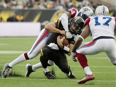 Hamilton Tiger-Cats quarterback Zach Collaros, centre, is tackled by Montreal Alouettes teammates Kyries Hebert (34) and Billy Parker (17) during first half CFL Eastern Division final football action in Hamilton, Ont., on Sunday, November 23, 2014.