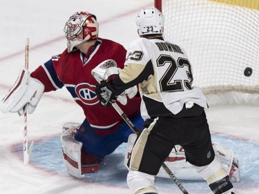 The puck goes into the net past Montreal Canadiens goalie Carey Price on a goal by Penguins' Beau Bennett as Pittsburgh Penguins' Steve Downie looks on during first period NHL hockey action Tuesday, November 18, 2014 in Montreal.