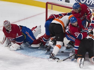 A loose puck is seen underneath a pile up next to Montreal Canadiens goalie Carey Price as Philadelphia Flyers' Matt Reid goes on to score on the play during third period NHL hockey action Saturday, November 15, 2014 in Montreal. The Canadiens defeated the Flyers 6-3.