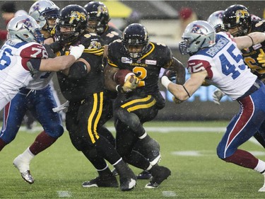 Hamilton Tiger-Cats running back Nic Grigsby (2) breaks for a hole between Montreal Alouettes defensive end Brian Brikowski (45) and defensive tackle Scott Paxson (76) during the first half of the CFL football game in Hamilton, Ont., on Saturday, November 8, 2014.