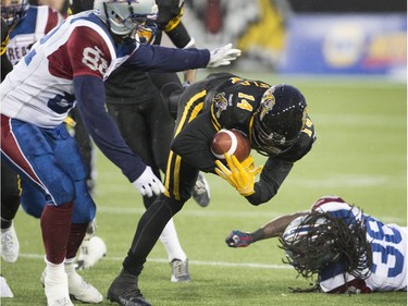 Hamilton Tiger-Cats wide receiver Terrell Sinkfield (14) stumbles after catching the ball while being defended by Montreal Alouettes long snapper Jerod Zaleski (82) during the first half of the CFL football game in Hamilton on Saturday, November 8, 2014.