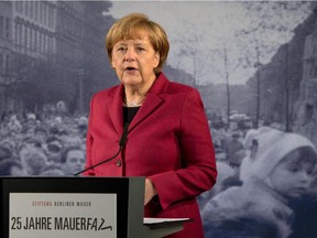 German Chancellor Angela Merkel delivers a speech in front of a giant reproduction of a photo dated from November 1989 as she opens an exhibition dedicated to the Berlin Wall during commemorations to mark the 25th anniversary of the fall of the Berlin Wall at the Berlin Wall Memorial in the Bernauer Strasse in Berlin, on Nov. 9, 2014.