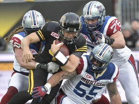 Hamilton Tiger-Cats quarterback Zach Collaros (centre) is tackled by Montreal Alouettes players (left to right) Bear Woods, Scott Paxson and Gabriel Knapton during second half action in the CFL Eastern Division final in Hamilton, Ont., on Sunday, Nov. 23, 2014.