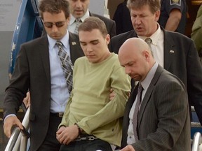 Luka Rocco Magnotta is taken by police from a Canadian military plane to a waiting van on Monday, June 18, 2012, in Mirabel, Quebec.