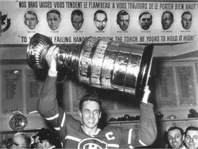 Jean Béliveau, who won 10 championships with the Canadiens, hoists the Stanley Cup in Habs locker room in front of line from In Flanders Fields poem.