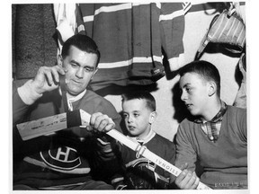 Canadiens legend Maurice (Rocket) Richard tapes a stick in the Canadiens dressing room during the 1959-60 season, watched by sons Normand (centre) and Maurice Jr.