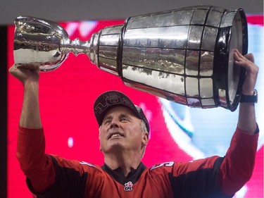 Wearing the jersey of the late John Forzani, Calgary Stampeders' head coach John Hufnagel, hoists the Grey Cup trophy after defeating the Hamilton Tiger-Cats to win the CFL championship game in Vancouver, B.C., on Sunday November 30, 2014.