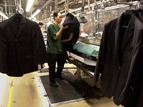 Chaojian, Yu presses men's jackets for sewing at the Peerless Clothing factory in 2004.