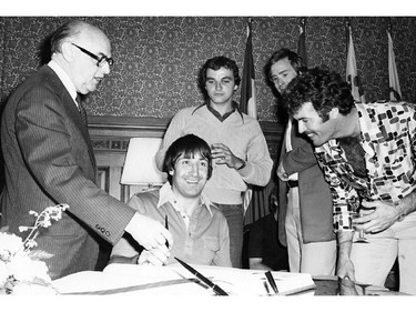 Montreal Canadiens defenceman Guy Lapointe signs the City of Montreal's Golden Book at City Hall, watched by Mayor Jean Drapeau (left), following a 1970s Stanley Cup victory. Other Canadiens, from left: Mario Tremblay, Ken Dryden, Yvon Lambert.
