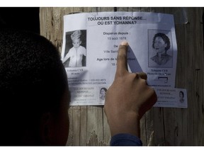 A young boy reads a missing person's poster for Yohanna Cyr, in Ville St. Laurent, Montreal, Thursday August 15, 2013. She disappeared 35 years ago  at 18-months old, and there was an event held by her family to remember her.