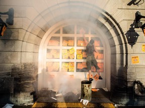 A protester supporting the firefighter's union places stickers on the garage door entrance to the Montreal City Hall building in protest of the proposed Bill 3, a pension reform bill, in Montreal on Monday, August 18, 2014.