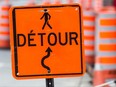 A detour sign amid construction cones.