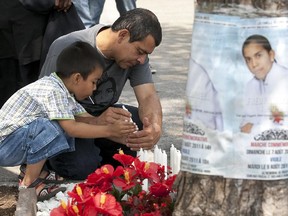 Gilberto Villanueva, right, and 5-year-old Deyvi Maldonado, father and nephew respectively of Fredy Villanueva, light candles at a memorial for Fredy Villanueva at Henri-Bourassa Park in Montreal, Sunday Aug. 7, 2011.