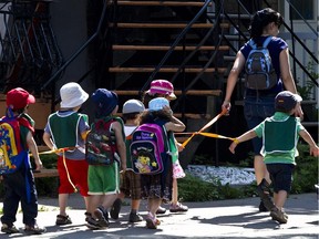 Children in daycare hold on to a rope as they walk with an adult in Rosemont in Montreal.