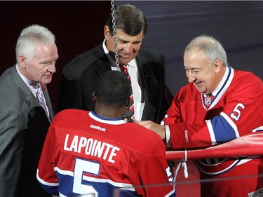 Guy Lapointe, right,  secures banner to cable  with P.K. Subban in front of  Serge Savard, and Larry Robinson, left, during the retirement of Lapointe's number at the Bell centre  in Montreal on Saturday November 08, 2014.