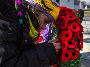 Four-year-old Layla Borquez Rooney attaches a poppy to a wreath at the cenotaph at the St-Jean Garrison in St-Jean-sur-Richelieu, on Tuesday, November 11, 2014 during the Remembrance Day ceremonies.