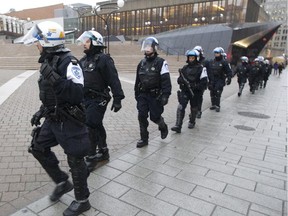 Montreal riot police walk past Place des Arts while pursuing protesters in Montreal, Wednesday, Nov. 12, 2014.