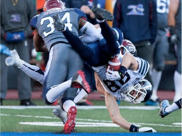Montreal Alouettes linebacker Kyries Hebert and Montreal Alouettes linebacker Winston Venable,rear, tackle Toronto Argonauts wide receiver Mike Bradwell during CFL action at the Molson Stadium in Montreal on Sunday November 2, 2014.