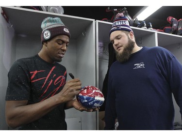 Montreal Alouettes receiver Duron Carter, left, autographs a souvenir football for team-mate Jeff Perrett as the team cleaned out their lockers at the Olympic Stadium in Montreal Monday November 24, 2014 one day after ending their season with a loss to Hamilton in the CFL Eastern Final.  Carter is expected to sign with an NFL team in the off-season.