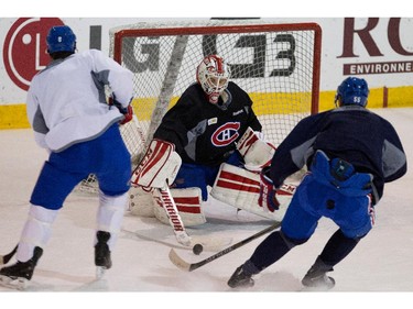 Montreal Canadiens goalie Dustin Tokarski, centre, stops Montreal Canadiens right wing Brandon Prust, left, as Montreal Canadiens defenseman Sergei Gonchar tries to take control of the loose puck during a team practice at the Bell Sports Complex  in Montreal on Thursday November 27, 2014.