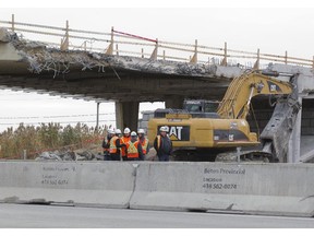 Workers at the demolition of the St. Grégoire overpass to highway 20, near highway 30 west of Montreal, Tuesday, November 4, 2014, after workers  discovered a crack in the overpass. The eastbound lane was closed to facilitate the work on the overpass.