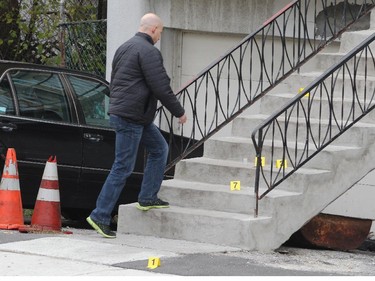 A Montreal Police investigator climbs stairs past evidence markers at the scene of a murder on Alfred W. Alfred-Thesserault St. in the Lachine borough of Montreal, Saturday November 8, 2014.
