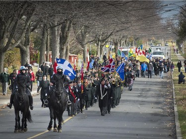 With 2 Montreal mounted police leading, Canadian veterans and soldiers from the Royal Montreal Regiment, march to the Pointe Claire Cenotaph for memorial day services on Sunday, Nov. 9, 2014.