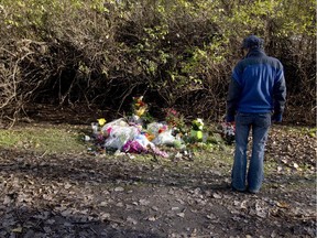 A passerby pauses to look at a makeshift memorial on a path in Longueuil south of Montreal, Sunday, Oct. 26, 2014, to honour Jenique Dalcourt who died after being found beaten on the path.
