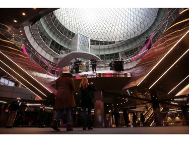 Commuters walk through the newly opened Fulton Center train station in lower Manhattan on November 10, 2014 in New York City.  The station was scheduled to open in 2007 as part of the rebuilding effort of lower Manhattan after 9/11, but the project ran into cost overruns and years of delays. The original plan for the facility, which has a glass and steel shell and 66,000 square feet of retail and office space, was projected at $750 million and nearly doubled to $1.4 billion before it was finished. The station features a 10-foot-high glass opening , or oculus, which sits above an atrium that lets sunlight down into two levels below street level. The station makes it easier to connect between nine subway lines: the A, C, J, Z, R, 2, 3, 4, and 5. Riders will eventually also be able to connect to the E and 1 trains, as well as the PATH.