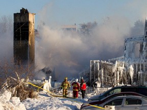 Firefighters stand by the smouldering remains of a seniors residence in L'Isle-Verte, Qc. Thursday Jan. 23, 2014.