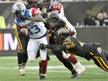 Hamilton Tiger-Cats linebacker Taylor Reed (right) dives to tackle Montreal Alouettes running back Brandon Rutley during second half action in the CFL Eastern Division final in Hamilton, Ont., on Sunday, Nov. 23, 2014.