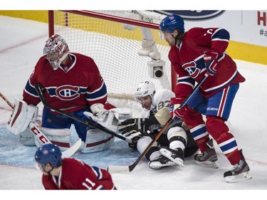 Sidney Crosby is dumped by defenceman Tom Gilbert in front of goalie Carey Price during first- period action Tuesday, Nov. 18, 2014, in Montreal.