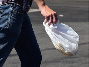 A man carries a plastic bag while leaving a supermarket.