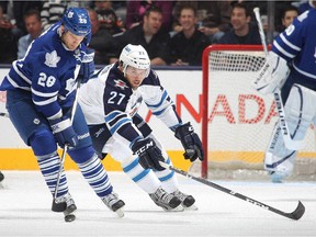 Eric Tangradi (No. 27) of the Winnipeg Jets tries to check the Maple Leafs' Colton Orr during NHL game on March 16, 2013 at the Air Canada Centre in Toronto.