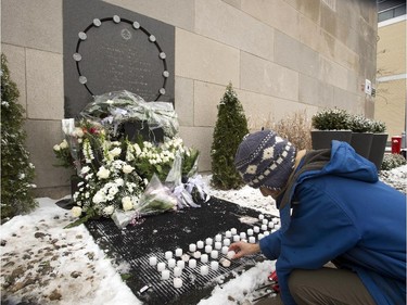 A woman lights a candle at the memorial plaque to mark the 25th anniversary of the Polytechnique massacre Saturday, December 6, 2014 in Montreal. It was 25 years ago Saturday that a gunman shot and killed 14 women before taking his own life at the École Poytechnique of the Université de Montréal.