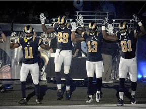 St. Louis Rams players raise their arms in awareness of the events in Ferguson, Mo.,  as they walk onto the field before an NFL football game against the Oakland Raiders on Nov. 30, 2014.