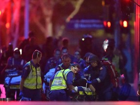 Australian paramedics work on an injured hostage as hostages are carried out of a cafe in the central business district of Sydney on December 16, 2014.