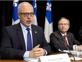 Quebec Finance Minister Carlos Leitao presents an economic update Tuesday, December 2, 2014 at the legislature in Quebec City. Quebec Treasury board president Martin Coiteux, right, looks on.