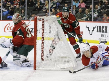 Montreal Canadiens right wing Dale Weise (22) falls as he brings the puck around the net in front of Minnesota Wild defenceman Jonas Brodin (25) as Wild goalie Darcy Kuemper, left,  covers the net during the second period of an NHL hockey game in St. Paul, Minn., Wednesday, Dec. 3, 2014.