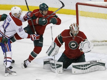 Minnesota Wild goalie Darcy Kuemper, right, deflects a shot as Wild defenceman Keith Ballard, centre, is tripped by Montreal Canadiens centre Lars Eller (81), of Denmark, during the first period of an NHL hockey game in St. Paul, Minn., Wednesday, Dec. 3, 2014.