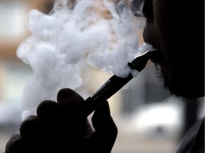 Daryl Cura demonstrates an e-cigarette at Vape store in Chicago, Wednesday, April 23, 2014. The federal government wants to ban sales of electronic cigarettes to minors and require approval for new products and health warning labels under regulations being proposed by the Food and Drug Administration.