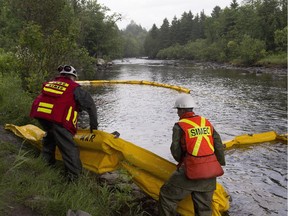 Environment workers lay booms on the Chaudière River near Lac-Mégantic, to contain the crude oil spill following a train derailment and explosion, Tuesday, July 9, 2013.