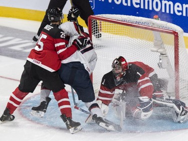 Canada goaltender Eric Comrie is sprayed as he makes a save off USA's Alex Tuch, covered by Canada defenceman Darnell Nurse, during first period hockey action at the IIHF World Junior Championship, Wednesday, December 31, 2014 in Montreal.
