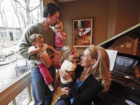 Former NFL tight end Ben Utecht kisses his daughter Amy, 1, while also holding Amy's twin sister Katriel, as Utecht's wife, Karyn, holds their daughter Elleora, 2, at their home in Lakeville, Minn., on Dec. 13, 2011.