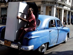 Aa man transports a new Chinese-made refrigerator in the trunk of a old car in Havana, Cuba, in 2012.